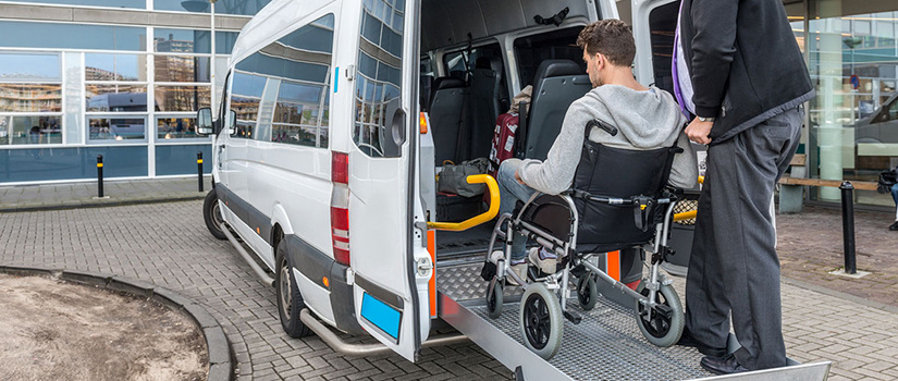 Illustration of a wheelchair user boarding an accessible ramp into a transport van